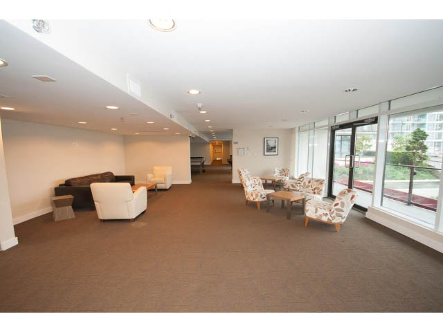 Spacious living room with large windows, city view, and modern furnishings. - 203 - 162 Victory Ship Way, North Vancouver