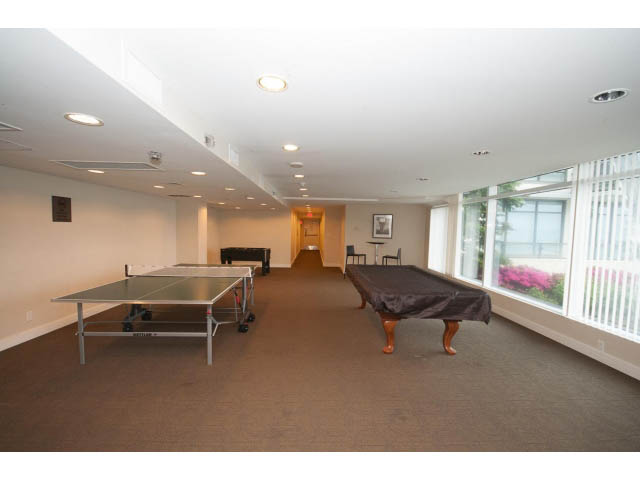 Bright living room with large windows and a ping pong table. - 203 - 162 Victory Ship Way, North Vancouver