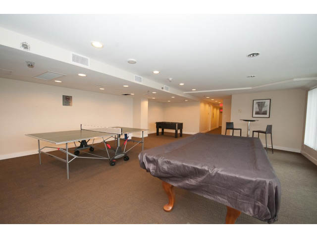 Furnished living room with ping pong table and covered furniture. - 203 - 162 Victory Ship Way, North Vancouver
