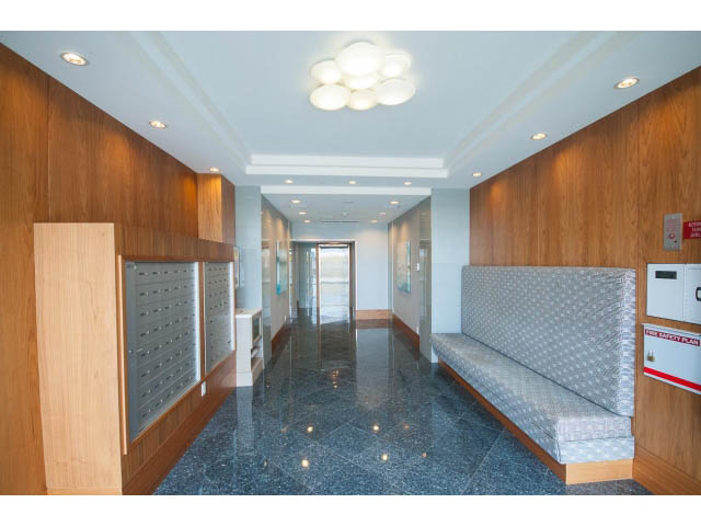 Spacious living room with polished marble floors and modern lighting fixtures. - 203 - 162 Victory Ship Way, North Vancouver