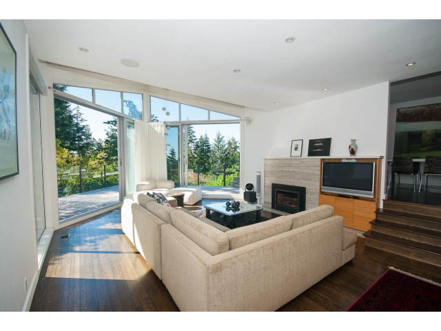 Spacious living room with large windows, hardwood floors, and a view of the trees. - 6190 Candia Place, West Vancouver