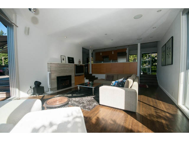 Open-concept living area with hardwood floors and a modern kitchen in the background. - 6190 Candia Place, West Vancouver