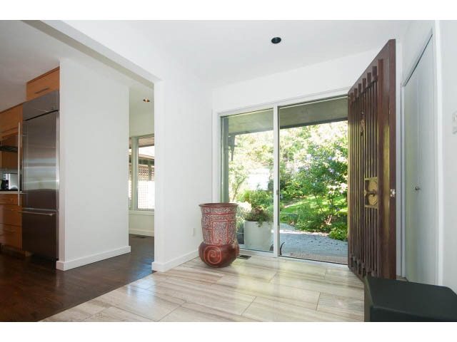 Bright kitchen with stainless steel appliances and hardwood floors, leading to a spacious living area with sliding glass...