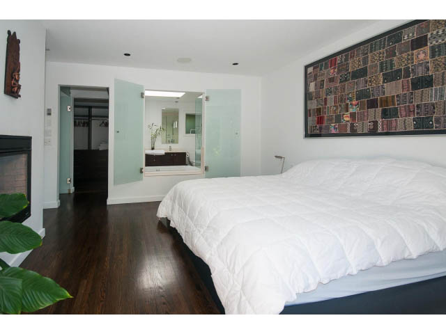 Spacious bedroom with white bedding, hardwood floors, and a large wall art piece. - 6190 Candia Place, West Vancouver