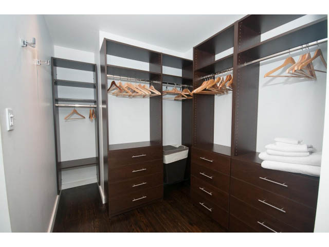 Furnished walk-in closet with dark wood cabinetry and hanging space. - 6190 Candia Place, West Vancouver