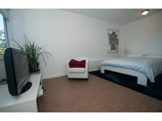 Furnished bedroom with white walls, a bed, and a small TV. - 6190 Candia Place, West Vancouver