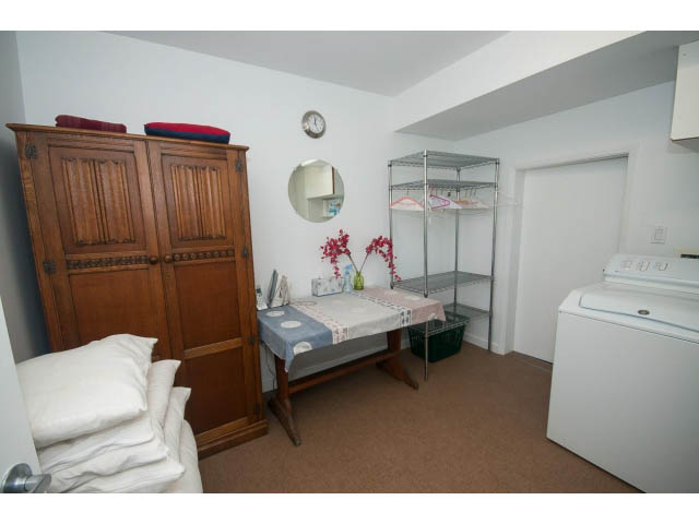 Bright bedroom with wooden wardrobe, white bedding, and a small round mirror. - 6190 Candia Place, West Vancouver