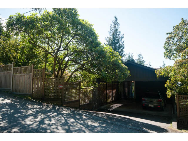 Fenced driveway leading to a house with lush greenery and a modern design. - 6190 Candia Place, West Vancouver