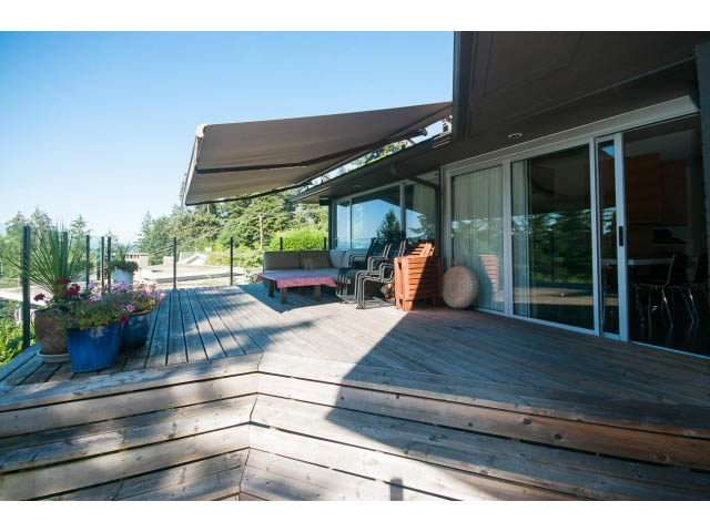 Furnished patio with wooden deck, sliding glass doors, and outdoor furniture. - 6190 Candia Place, West Vancouver