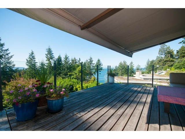 Furnished patio with wooden deck, potted plants, and scenic view. - 6190 Candia Place, West Vancouver