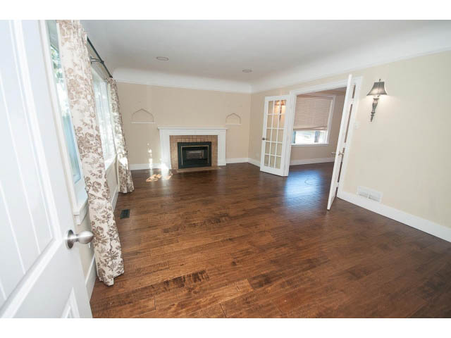 Spacious living room with hardwood floors and a fireplace, leading to a French door. - 2939 West 30th Ave, Vancouver West Side