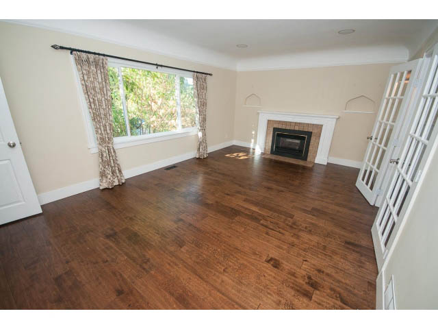 Bright living room with hardwood floors and a fireplace, large windows with curtains. - 2939 West 30th Ave, Vancouver West Side