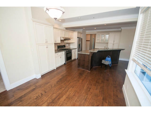Bright kitchen with hardwood floors and stainless steel appliances, open to living area. - 2939 West 30th Ave, Vancouver West Side