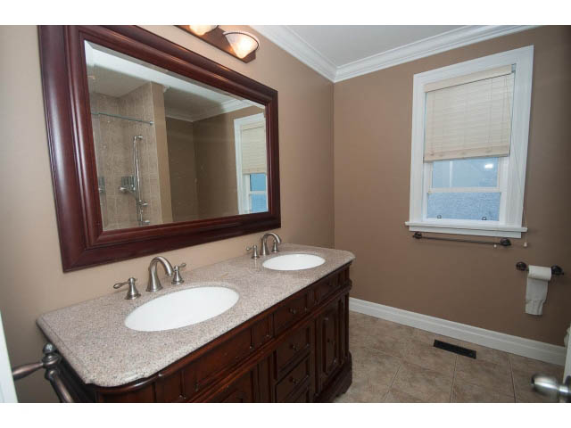 Spacious bathroom with granite countertops and a large mirror, featuring a city view through the window. - 2939 West 30th Ave, Vancouver West Side