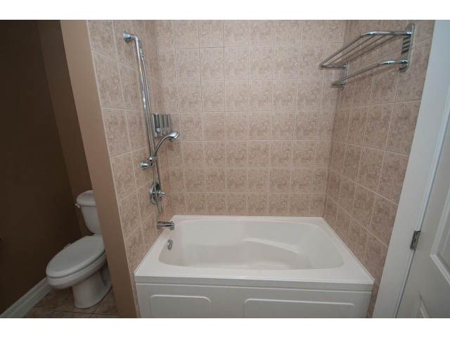 Bathroom with corner bathtub, tiled walls, and chrome fixtures. - 2939 West 30th Ave, Vancouver West Side