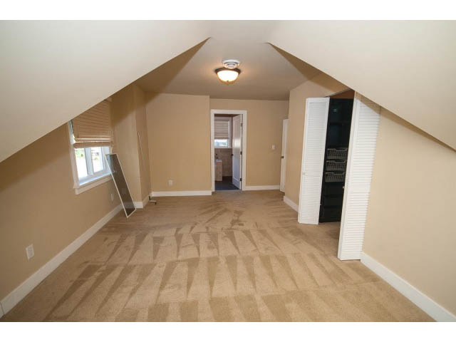 Attic space with sloped ceilings, carpeted floors, and a small window. - 2939 West 30th Ave, Vancouver West Side