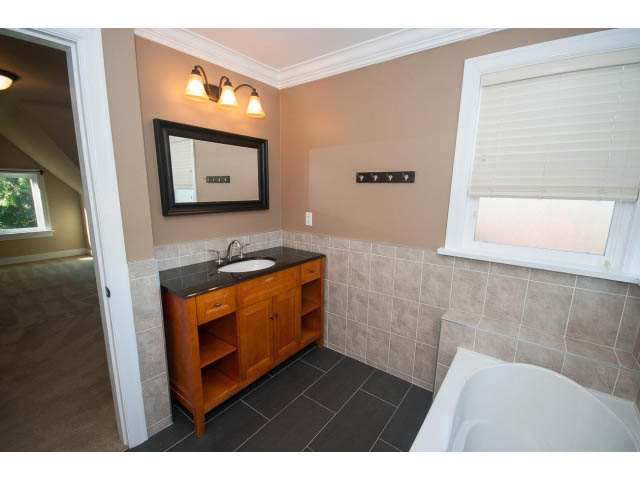 Spacious bathroom with wooden vanity, tiled walls, and large window. - 2939 West 30th Ave, Vancouver West Side