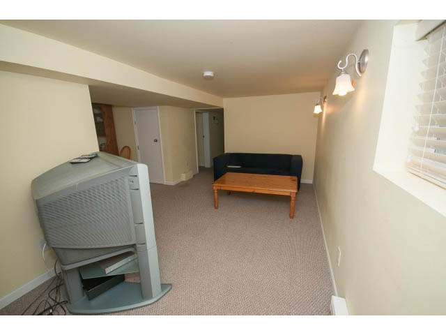 Living room with beige carpet, small TV, and wooden furniture. - 2939 West 30th Ave, Vancouver West Side