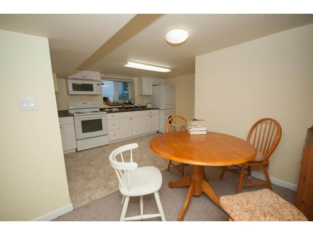 Furnished kitchen with white cabinets and a wooden dining table, clean and inviting. - 2939 West 30th Ave, Vancouver West Side