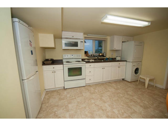 Bright kitchen with white cabinets, stainless steel appliances, and tiled flooring. - 2939 West 30th Ave, Vancouver West Side