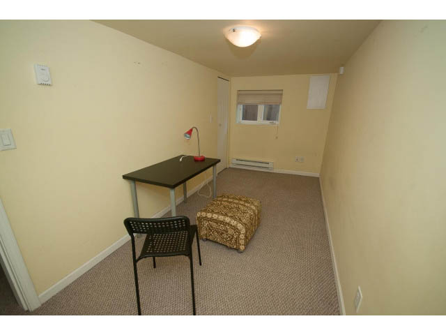 Small bedroom with beige walls, carpeted floor, and a desk with a lamp. - 2939 West 30th Ave, Vancouver West Side