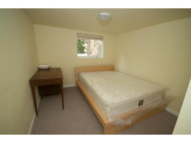Small bedroom with two single beds, carpeted floor, and a small window. - 2939 West 30th Ave, Vancouver West Side