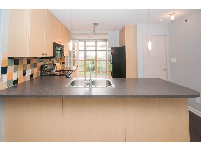 Bright kitchen with modern countertops and a colorful backsplash, featuring a city view through the window.