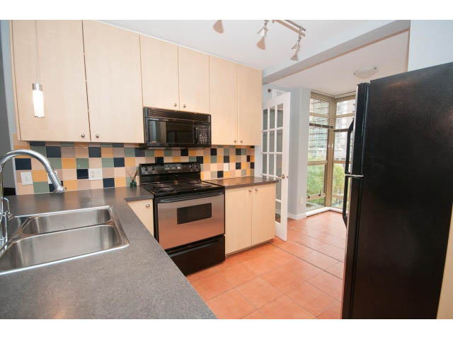 Bright kitchen with modern appliances, black countertops, and terracotta tile flooring. - 602 - 819 Hamilton Street, Vancouver Downtown