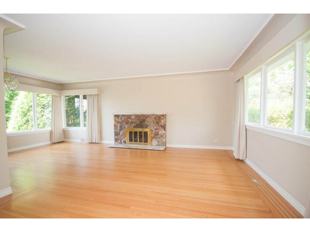 Spacious living room with hardwood floors, fireplace, and large windows. - 221 Carisbrooke Crescent, North Vancouver
