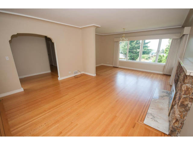 Bright living room with hardwood floors and a city view through large windows. - 221 Carisbrooke Crescent, North Vancouver