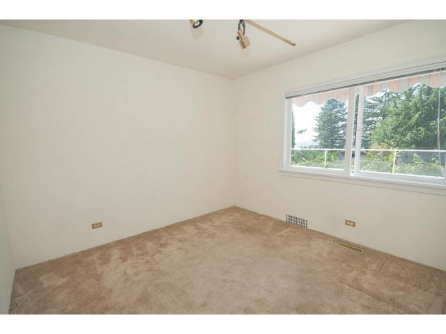 Bright bedroom with carpeted floor and large window view of trees. - 221 Carisbrooke Crescent, North Vancouver