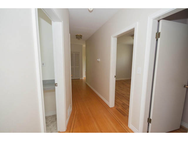 Bright hallway with hardwood floors and white walls leading to a room with a closet. - 221 Carisbrooke Crescent, North Vancouver