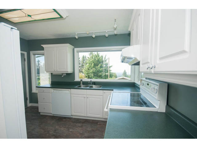 Bright kitchen with white cabinets, dark countertops, and a city view. - 221 Carisbrooke Crescent, North Vancouver