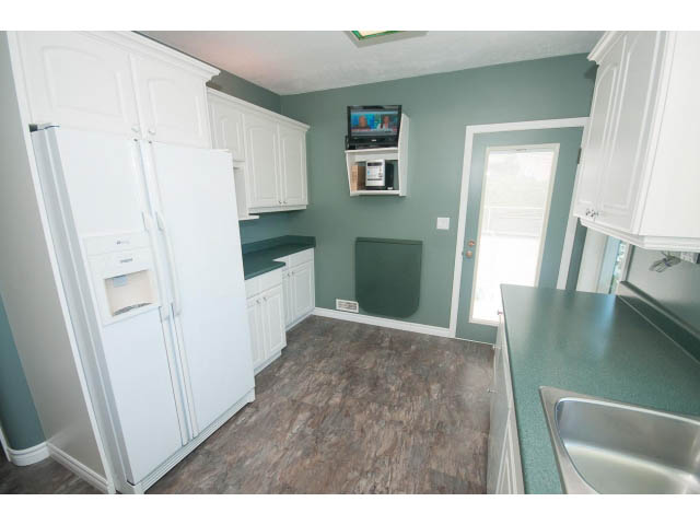 Bright kitchen with green walls, white cabinets, and granite countertops. - 221 Carisbrooke Crescent, North Vancouver