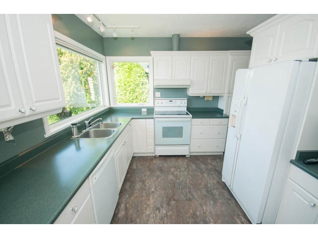 Bright kitchen with white cabinets, dark countertops, and hardwood floors. - 221 Carisbrooke Crescent, North Vancouver