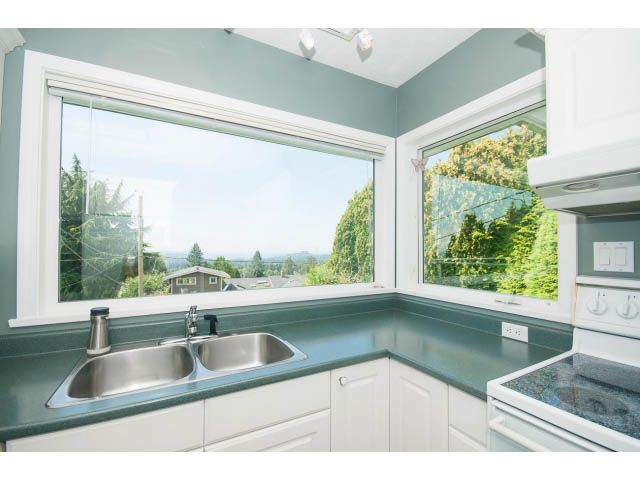 Bright kitchen with green countertops and a city view through large windows. - 221 Carisbrooke Crescent, North Vancouver