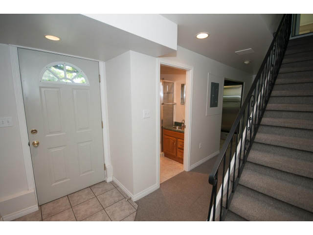Foyer with tiled floor, arched door, and carpeted staircase leading to upper levels. - 221 Carisbrooke Crescent, North Vancouver