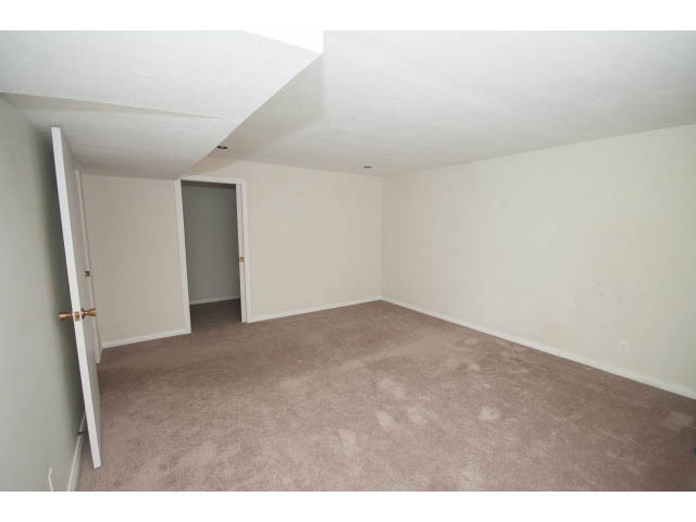 Bright living room with beige carpet and white walls, door leading to another room. - 221 Carisbrooke Crescent, North Vancouver