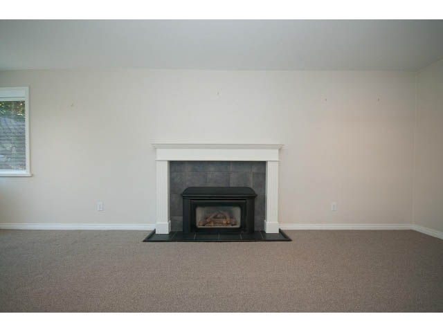 Empty living room with fireplace and neutral carpeting. - 221 Carisbrooke Crescent, North Vancouver