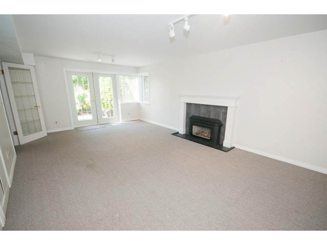 Spacious living room with fireplace, carpeted floors, and sliding glass doors leading outside. - 221 Carisbrooke Crescent, North Vancouver