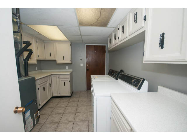 Bright laundry room with white cabinets, tiled floor, and washing machine. - 221 Carisbrooke Crescent, North Vancouver
