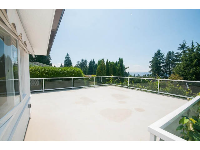 Bright balcony with white railings, overlooking green trees and a clear sky. - 221 Carisbrooke Crescent, North Vancouver