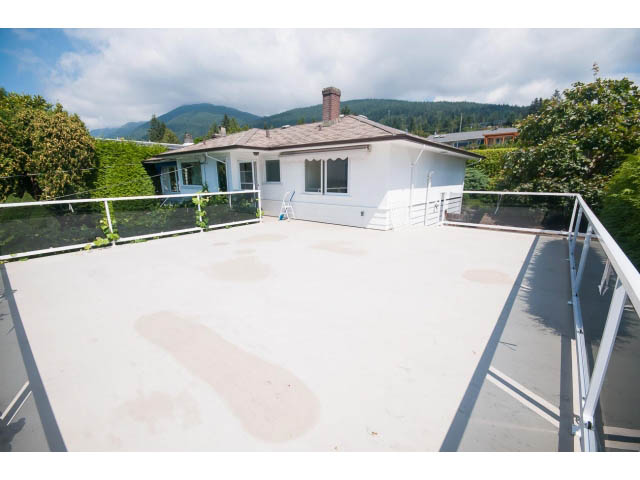 Bright rooftop deck with white railings, overlooking greenery and mountains. - 221 Carisbrooke Crescent, North Vancouver