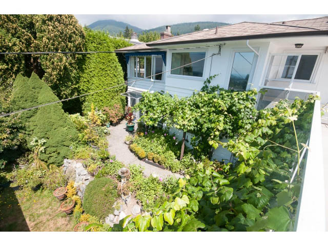 Furnished living room with lush greenery and mountain view. - 221 Carisbrooke Crescent, North Vancouver