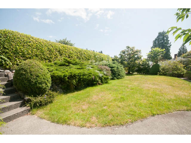 Landscaped front yard with neatly trimmed hedges and a stone pathway leading up to the house. - 221 Carisbrooke Crescent, North Vancouver