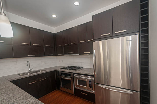 Bright kitchen with dark wood cabinets, stainless steel appliances, and granite countertops. - 2753 Guelph Street, Vancouver East Side