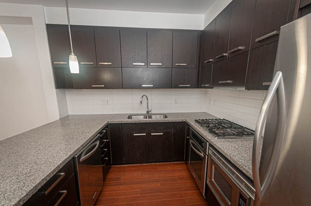 Bright kitchen with dark wood cabinets, granite countertops, and stainless steel appliances. - 2753 Guelph Street, Vancouver East Side