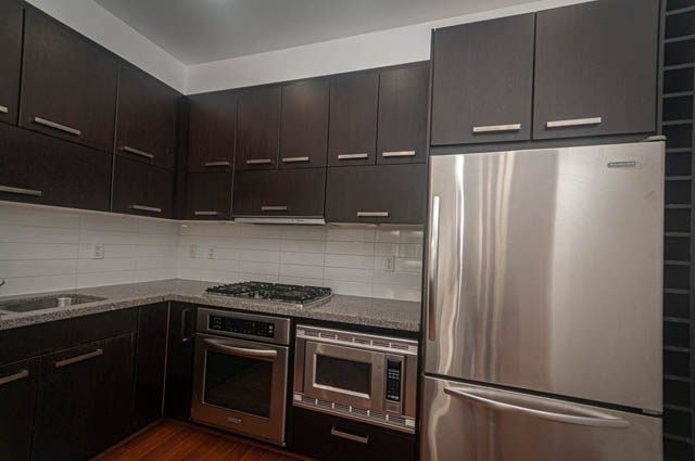 Bright kitchen with dark cabinets, stainless steel appliances, and granite countertops. - 2753 Guelph Street, Vancouver East Side