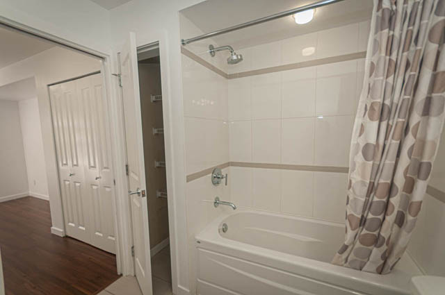 Bright bathroom with white tiles and a shower curtain. - 2753 Guelph Street, Vancouver East Side