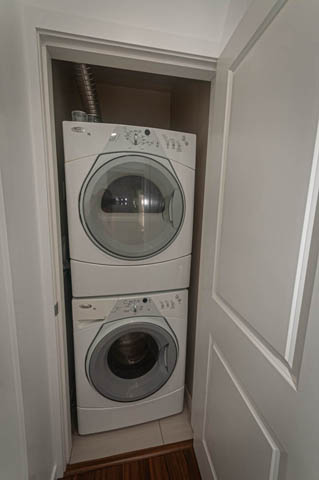 Bright laundry room with stacked washer and dryer, hardwood floors. - 2753 Guelph Street, Vancouver East Side